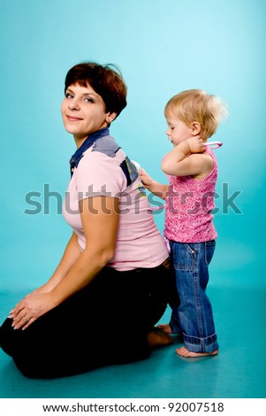 Mother and daughter playing doctor and patient. Isolated on turquoise