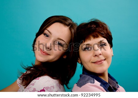 Happy middle-aged mother and teenage daughter. Close-up. Isolated on turquoise
