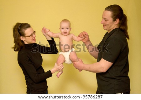 Mother and father are doing  physical fitness exercises together with baby. Isolated on yellow