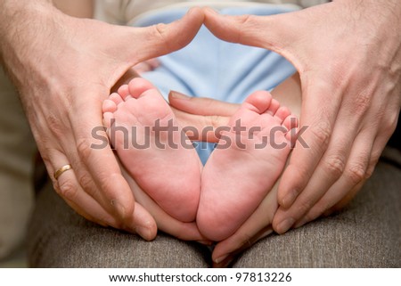 Baby feet in father and the my mother\'s hands, heart-shaped.  The symbol of protection, custody and parental love