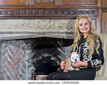 Woman sitting by a fireplace with a dog puppy in luxury interior