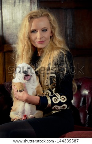 Blonde woman with an english bulldog puppy dog in luxury room