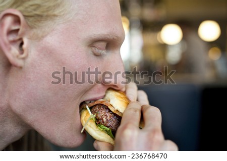 Young man eating big burger
