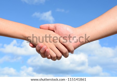 Partner hand between a man and a woman on blue sky background, Teamwork