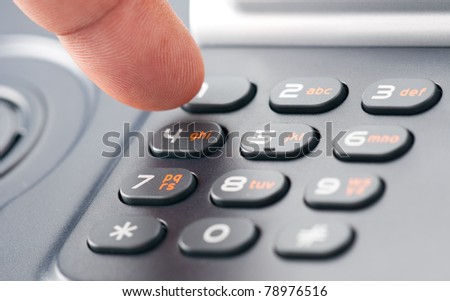 A finger dialing on a phone keypad