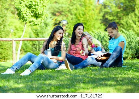 four smiling student girls studying in green park