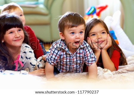 group of happy kids watching tv at home