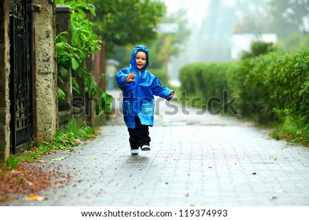 happy baby boy running the street under the rain