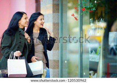 two happy elegant women looking in shop window