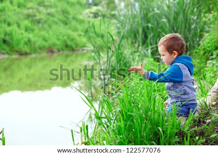 lonely little boy sitting in cane on riverside, throwing stones