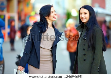 happy female friends walking the crowded city street