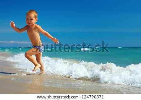 happy baby running from surf on the beach happy baby running from surf on the beach