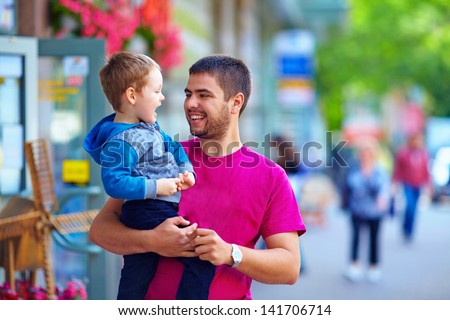 candid image of father and son walking crowded street