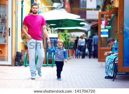 candid image of father and son walking the street