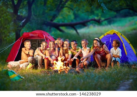 Group Of Happy Kids Roasting Marshmallows On Campfire