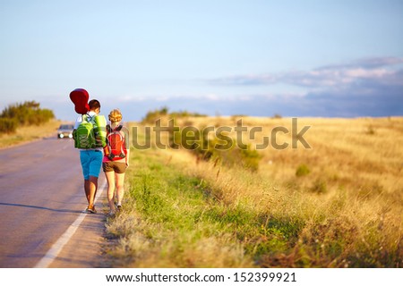 young people traveling hitchhiking. summer field