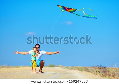 father and son having fun, playing with kite together
