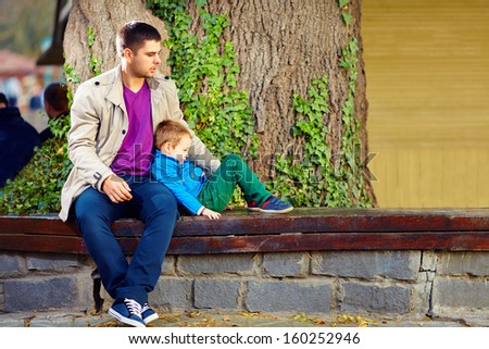 stylish father and son on the bench, in front of old tree