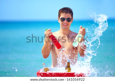 happy man with drinks and water splash on the beach party