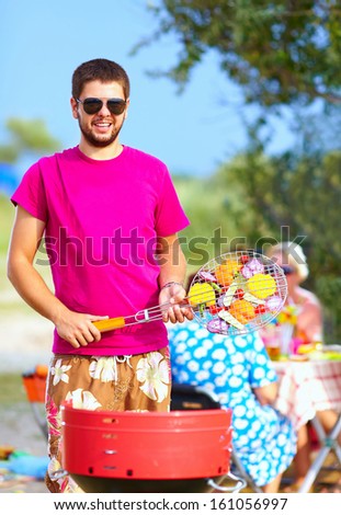happy man prepares food on the grill, family picnic