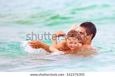 happy father and son swimming in sea water