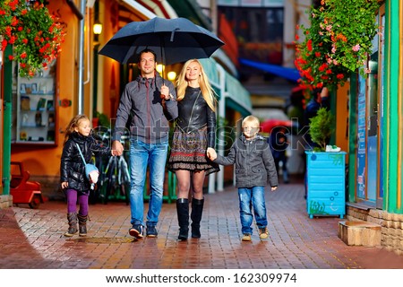 happy family walking under the rain on cozy colorful street