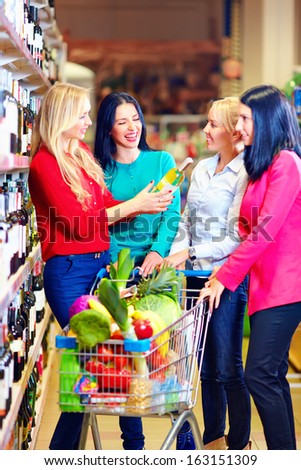 group of beautiful girls choosing wine in supermarket