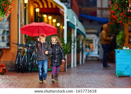 happy kids walking the street under the rain