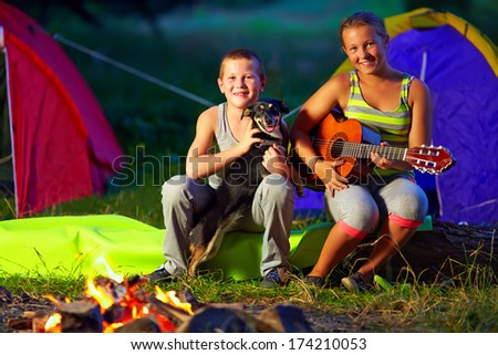 happy teenagers singing songs around camp fire