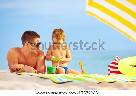 happy father and child playing in sand on the beach