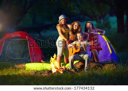 happy teens together around camp fire