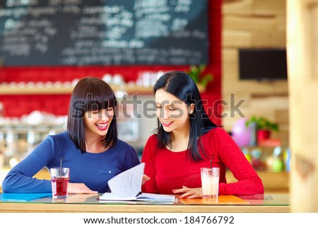 pretty female friends studying in cafe