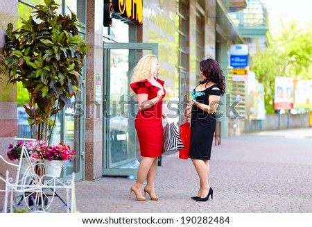 happy plus size women shopping, talking on the street