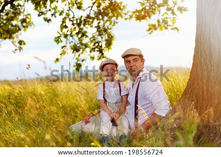 father and son sitting under an old oak tree