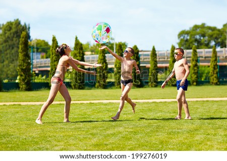 group of teenage kids playing with ball on summer lawn