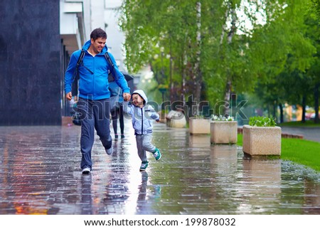 happy father and son running under the rain