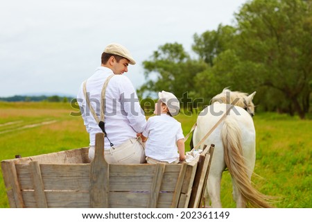 father and son, farmers ride a horse cart