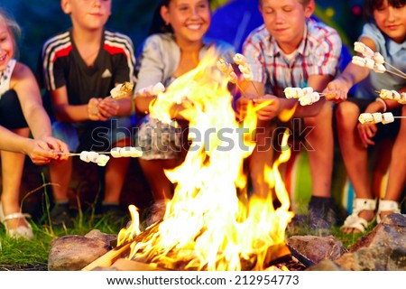 happy kids roasting marshmallows on campfire