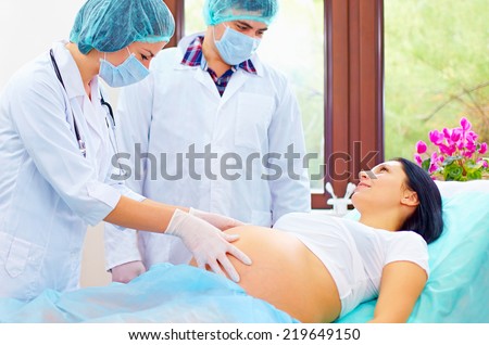 doctor palpates the abdomen of pregnant woman before childbirth
