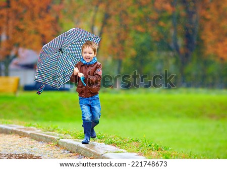 happy boy running under an autumn rain