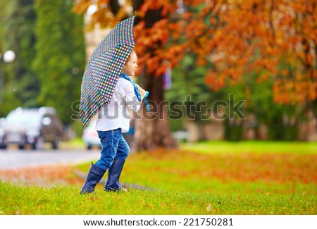 cute boy enjoying an autumn rain in city park