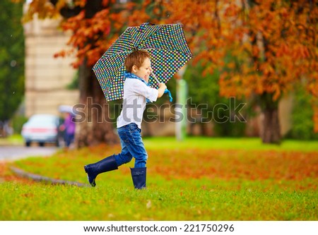 cute boy enjoying an autumn rain in city park