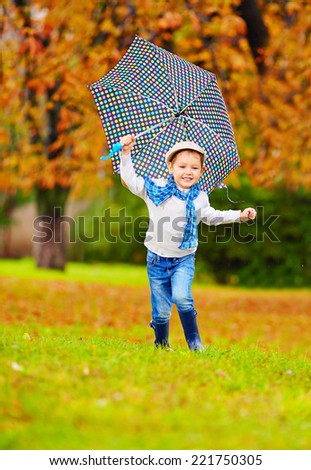 happy boy enjoying an autumn rain in park