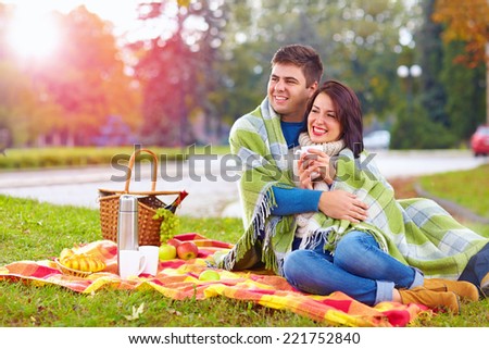 happy couple enjoying autumn picnic in city park