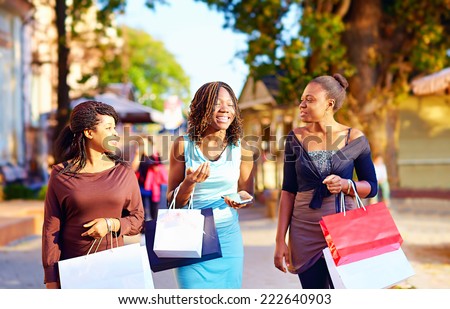 happy african girls walking the street with shopping bags