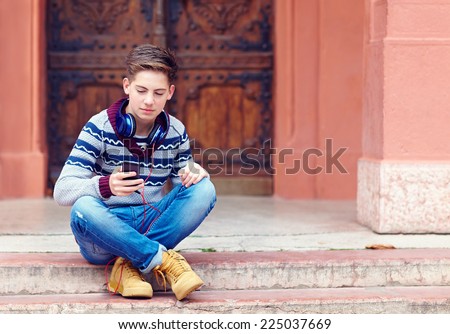 stylish teenage boy listens to the music on smart phone