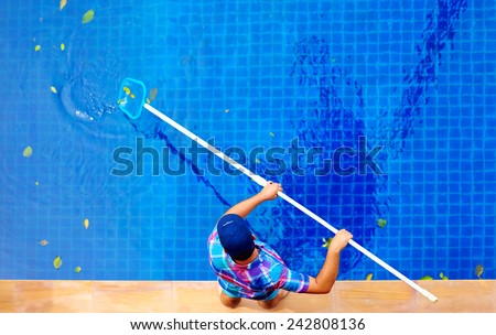 young adult man, personnel cleaning the pool from leaves