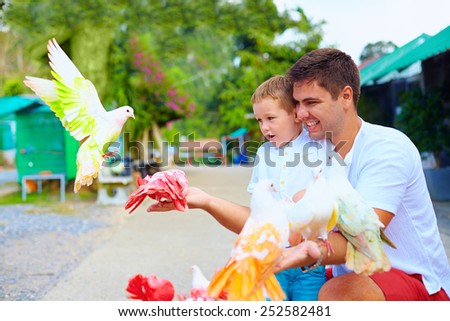 excited family feeding colorful pigeons on animal farm