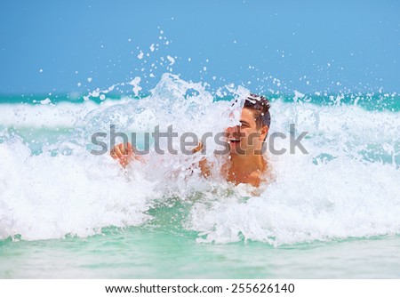 handsome man enjoys swimming in sea waves