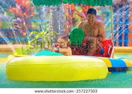 family drive watercraft in aqua park, trying to hit each other